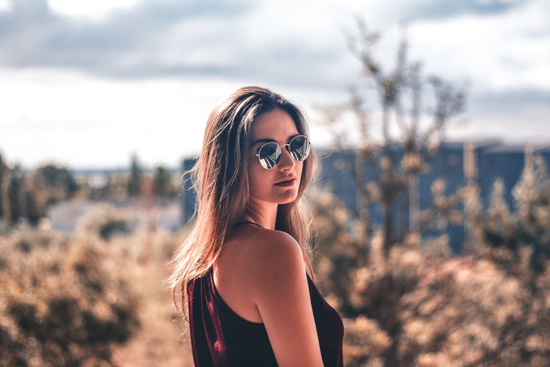 Young woman with sunglasses posing for photo while hiking