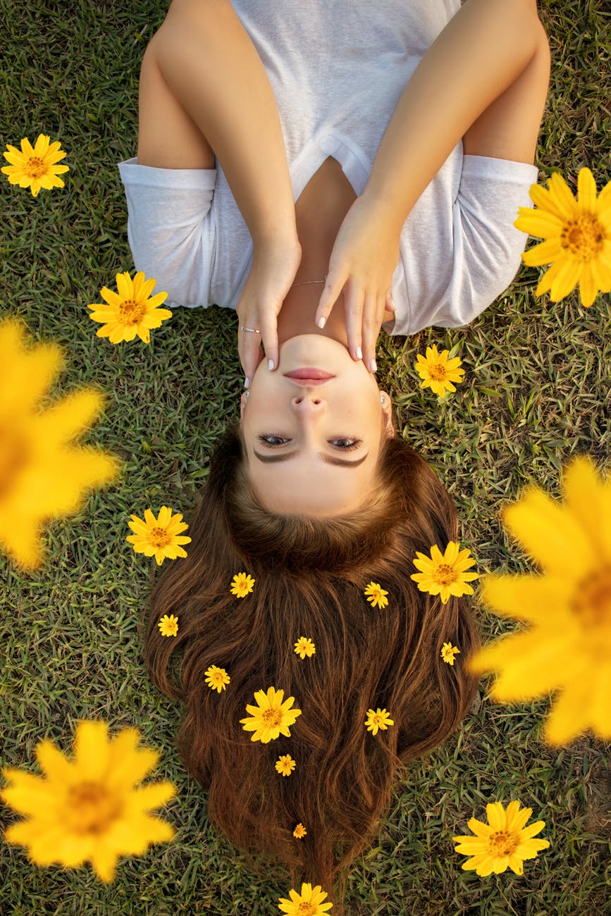 Woman lying on grass surrounded by sunflowers