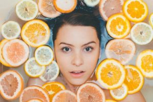 Close up of woman's face in bathtub surrounded by floating orange and lemon peels