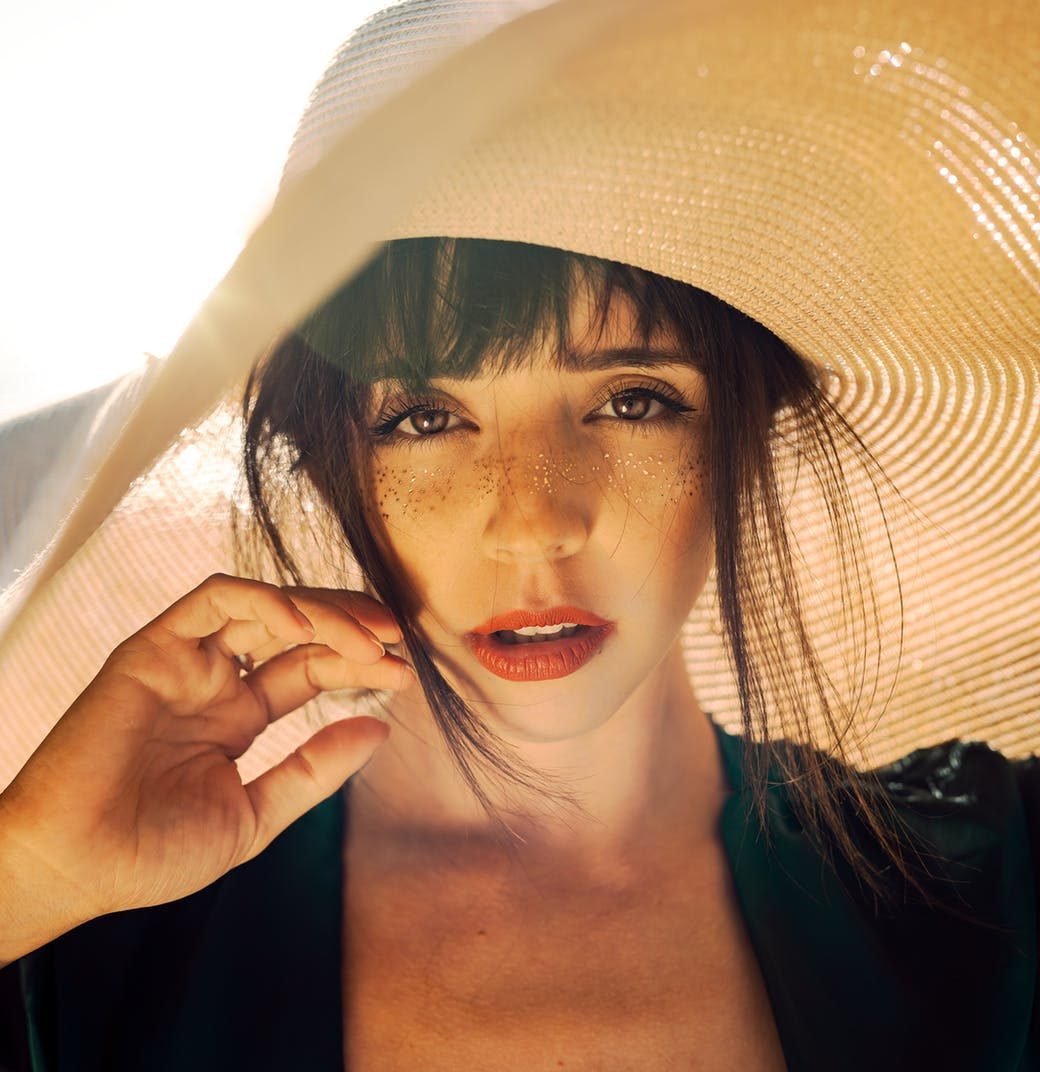 Young woman with sun hat staring directly into camera lens